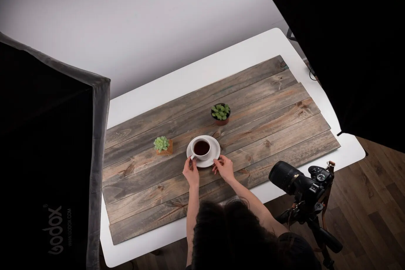 Vista desde arriba de un fotógrafo acomodando una taza de té para una sesión de fotos en estudio.